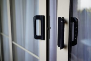 Black handles on double-glazed uPVC sliding doors with sheer curtains demonstrate an energy-efficient sliding door solution.