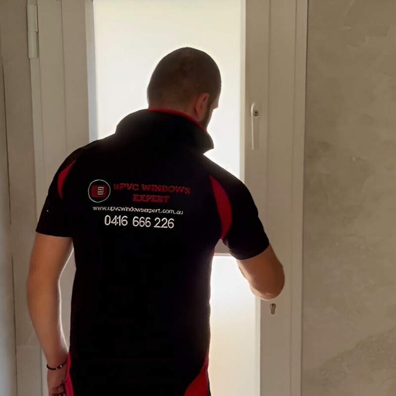 A man wearing a black and red shirt is in the process of opening a uPVC door in Aylmerton. He is an installer working for uPVC Windows Expert doing door installation service.