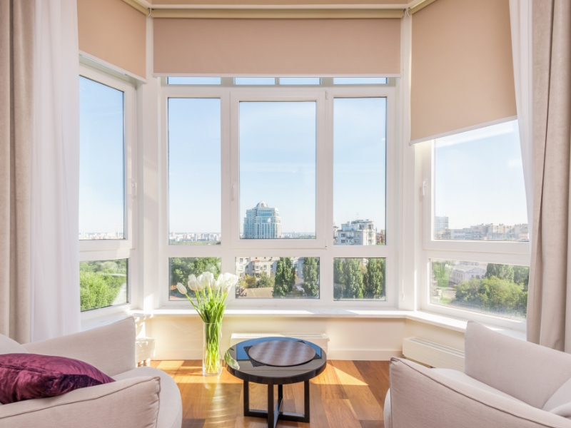 A stylish living room featuring customised uPVC French style windows, offering a panoramic view of the city skyline.