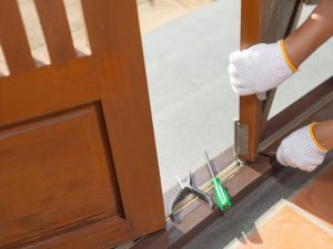 Close-up of a person adjusting hinges during bifold glass door installation or maintenance, tools placed nearby.