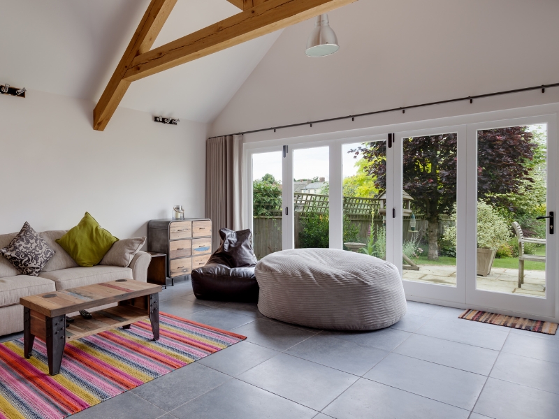 Spacious living room with large bifold glass doors opening to a lush garden, enhancing natural light.