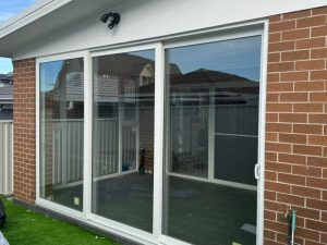 Modern home exterior with large glass slide in doors, showcasing a stylish and functional entrance solution.