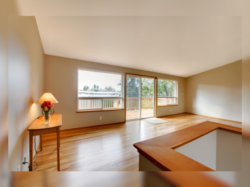 Spacious living room with wooden floors and slide in doors leading to a deck, enhancing natural light flow.