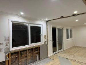 Partially renovated interior space with newly installed sliding glass doors and windows.