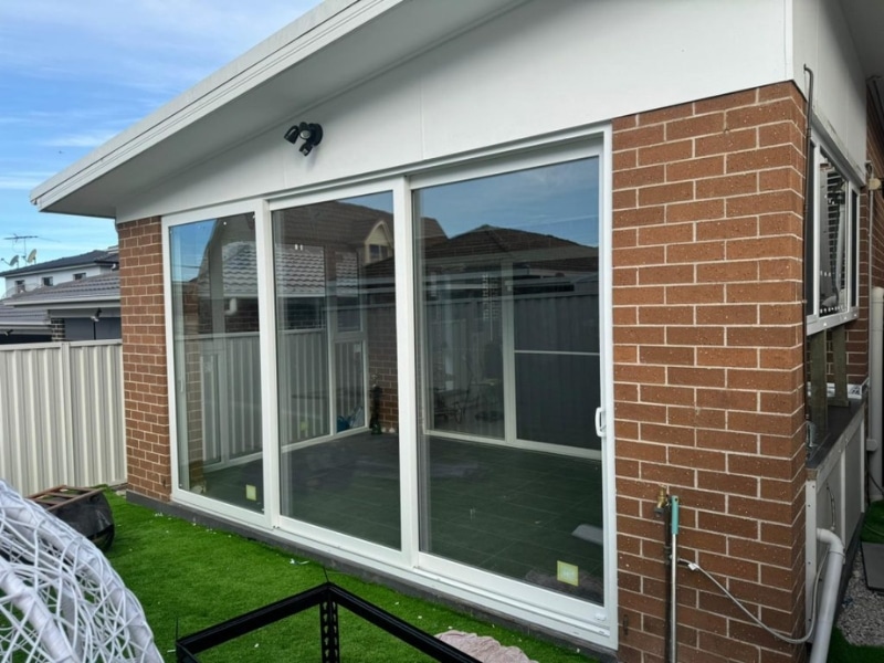 Modern home exterior featuring a white upvc sliding door frame with large glass panels.