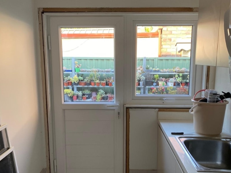 Modern kitchen showing upvc windows installation with white frames overlooking outdoor garden.