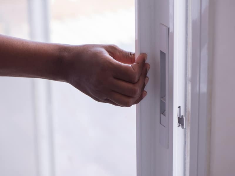 Close-up of a hand opening a white upvc sliding door frame handle.