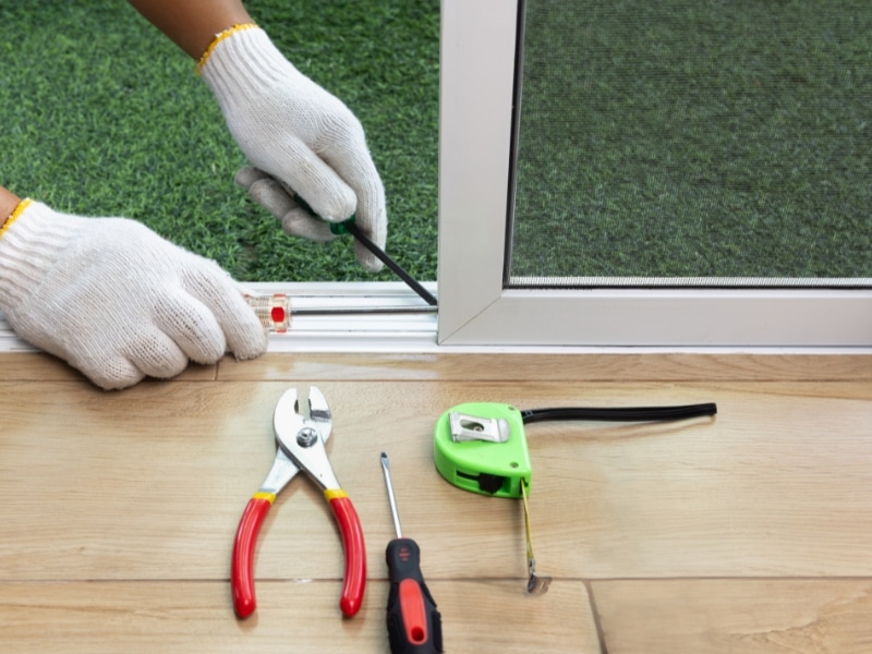 Tools and technician aligning track while fitting a sliding door.