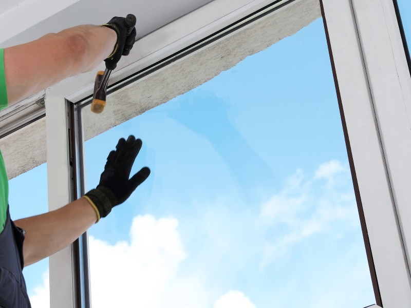 Professional worker installing double glazed windows to improve home insulation.