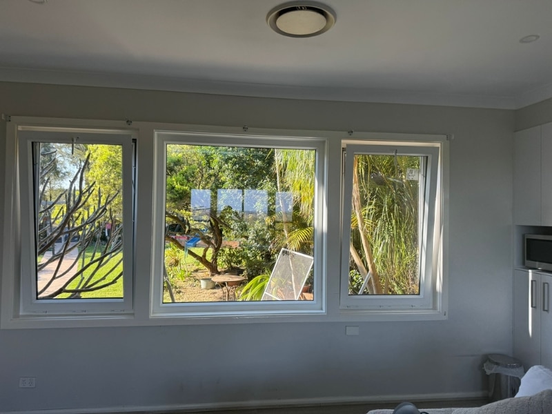 Interior view of three newly installed windows in a bright room, demonstrating variables in the cost of replacing windows with double glazing.