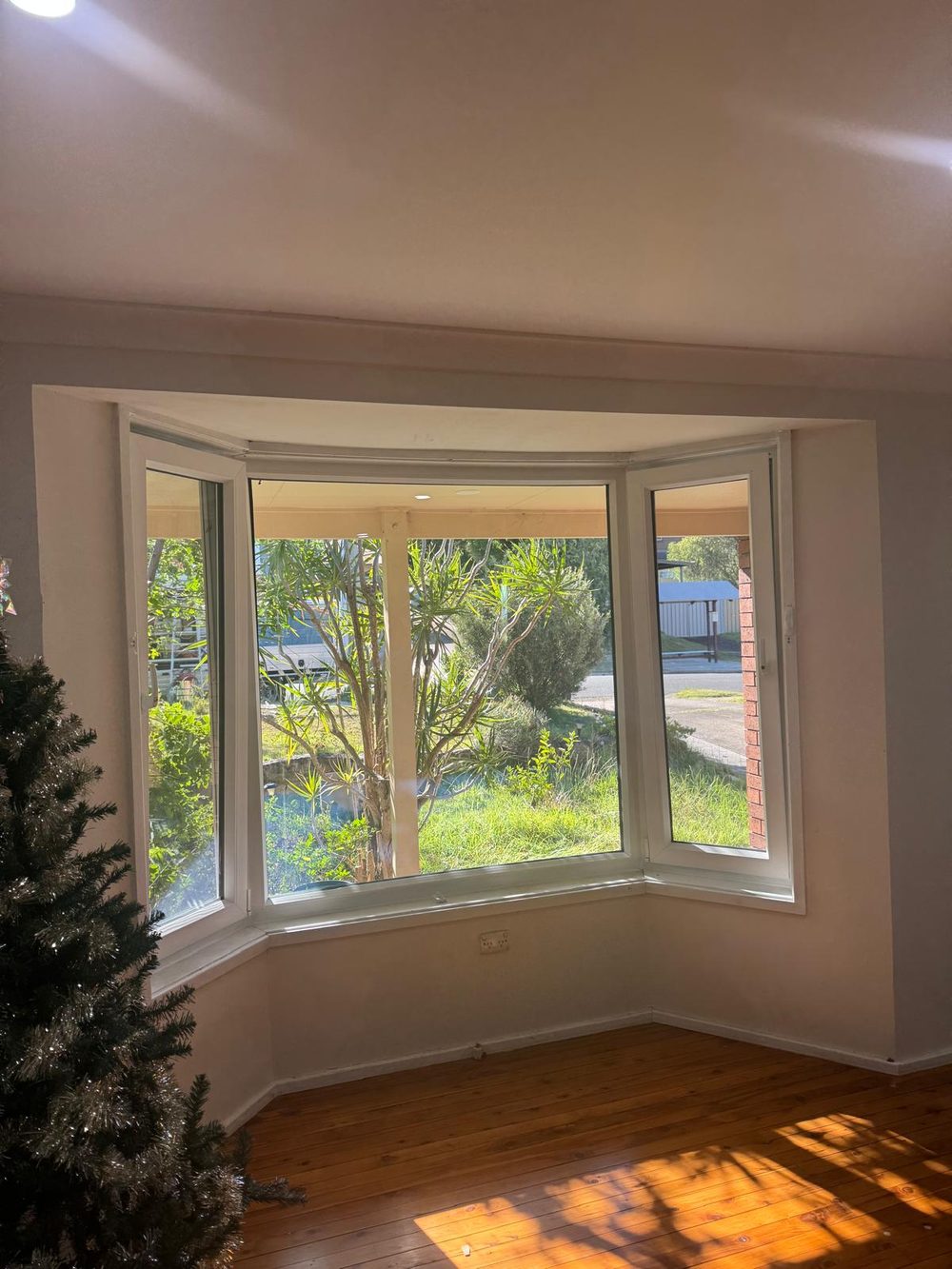 White uPVC bay window with timber floor and garden outlook in an Australian period style home
