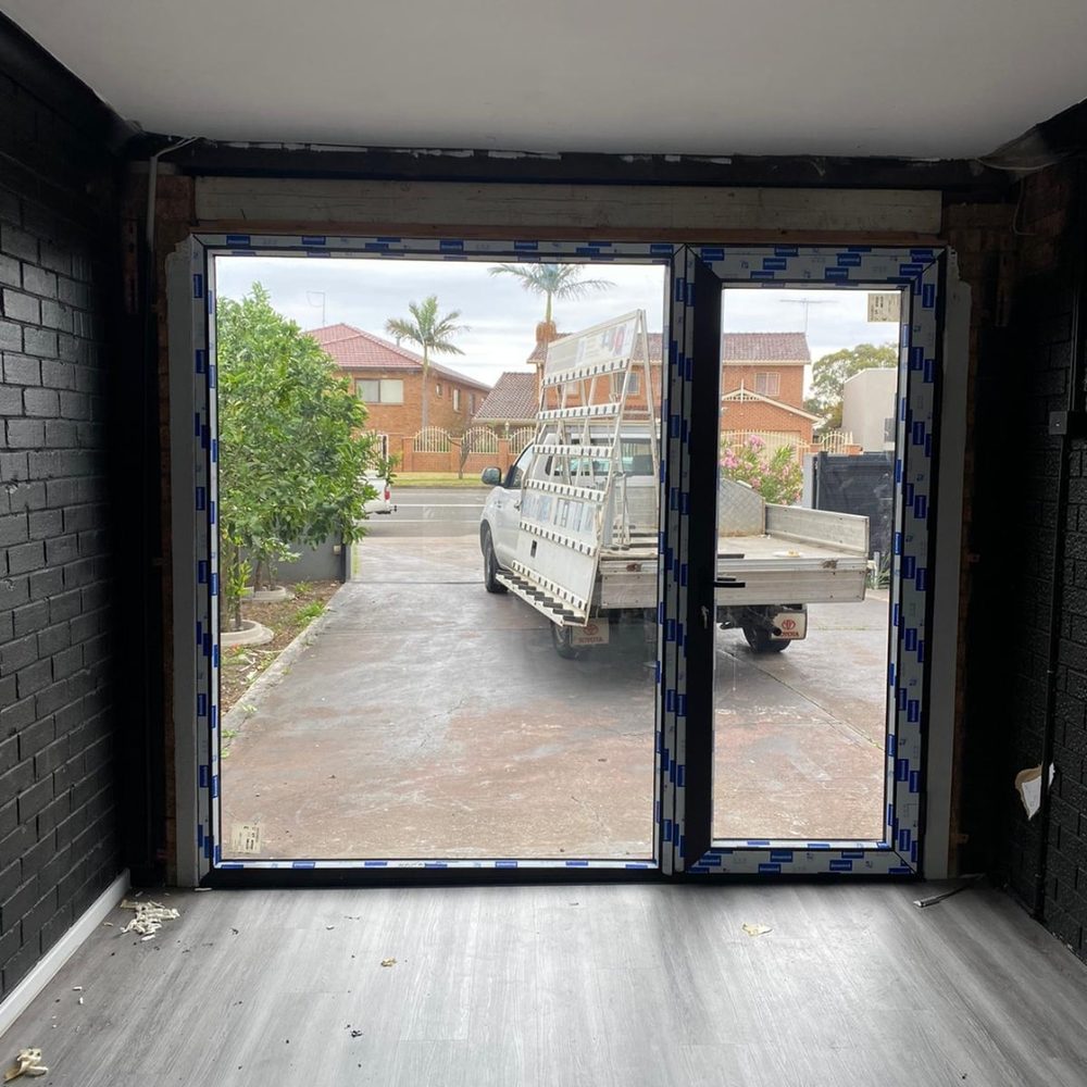 Dark framed uPVC double doors being installed in an Australian home, with protective film still on the frames