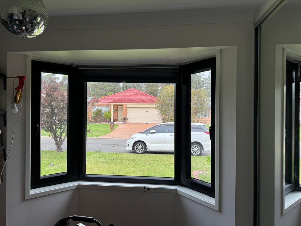 Black framed uPVC bay window in a living room looking out to a suburban street and parked car